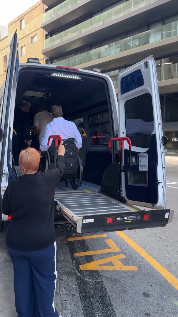 Screenshot 2026-09-17 200244 Accessible vehicle with a wheelchair lift deployed, showing a person using a wheelchair boarding the vehicle.